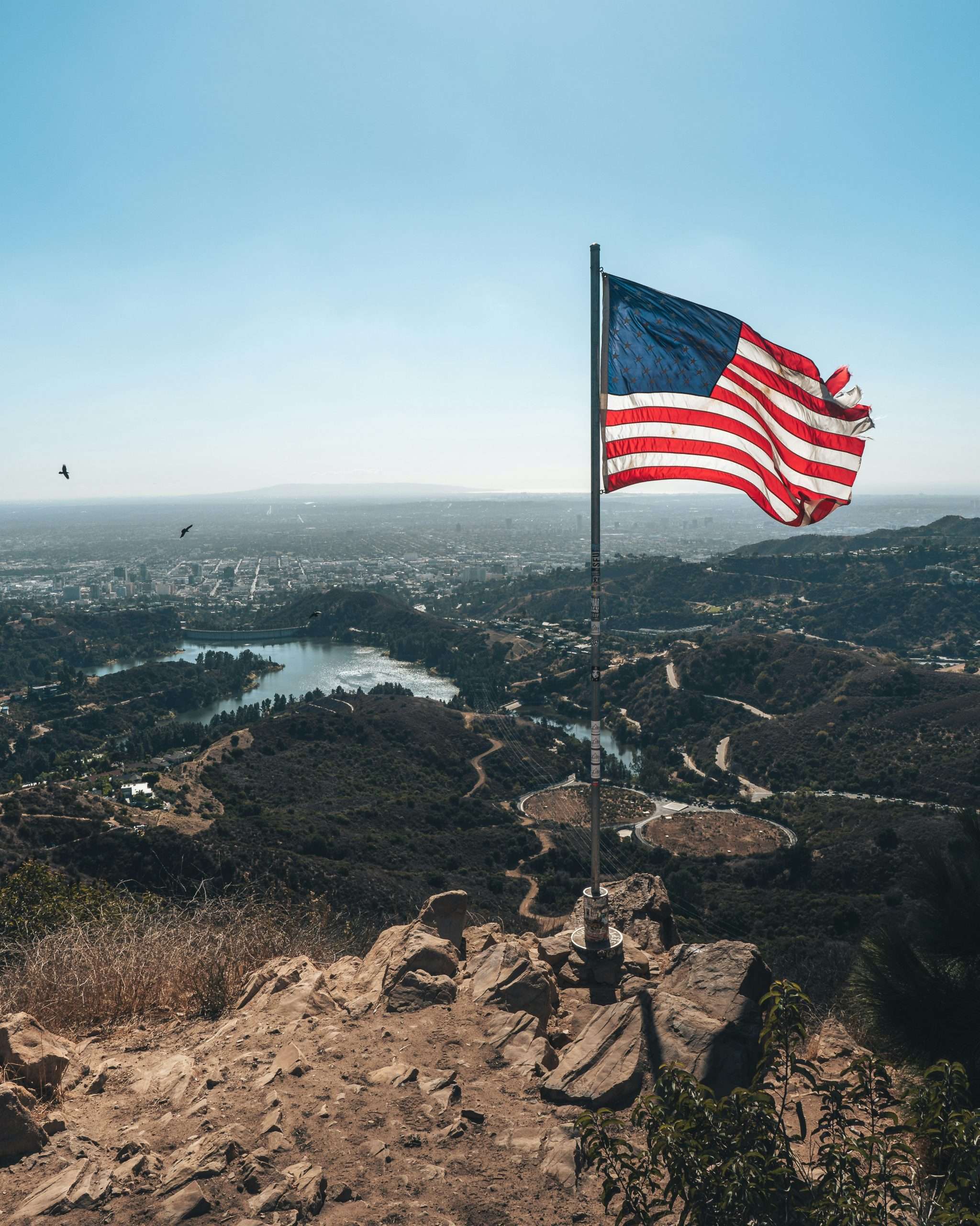 blake-lee-_XAFoSPQYZA-unsplash American flag flying over scenic landscape view.