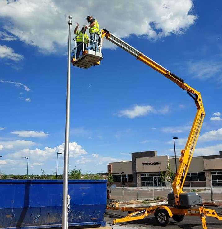 Workers on crane fixing a tall streetlight pole