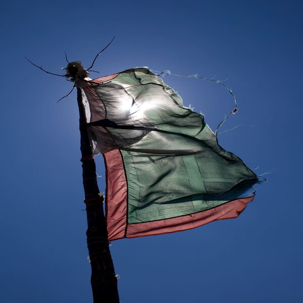 Tattered flag against bright blue sky background.