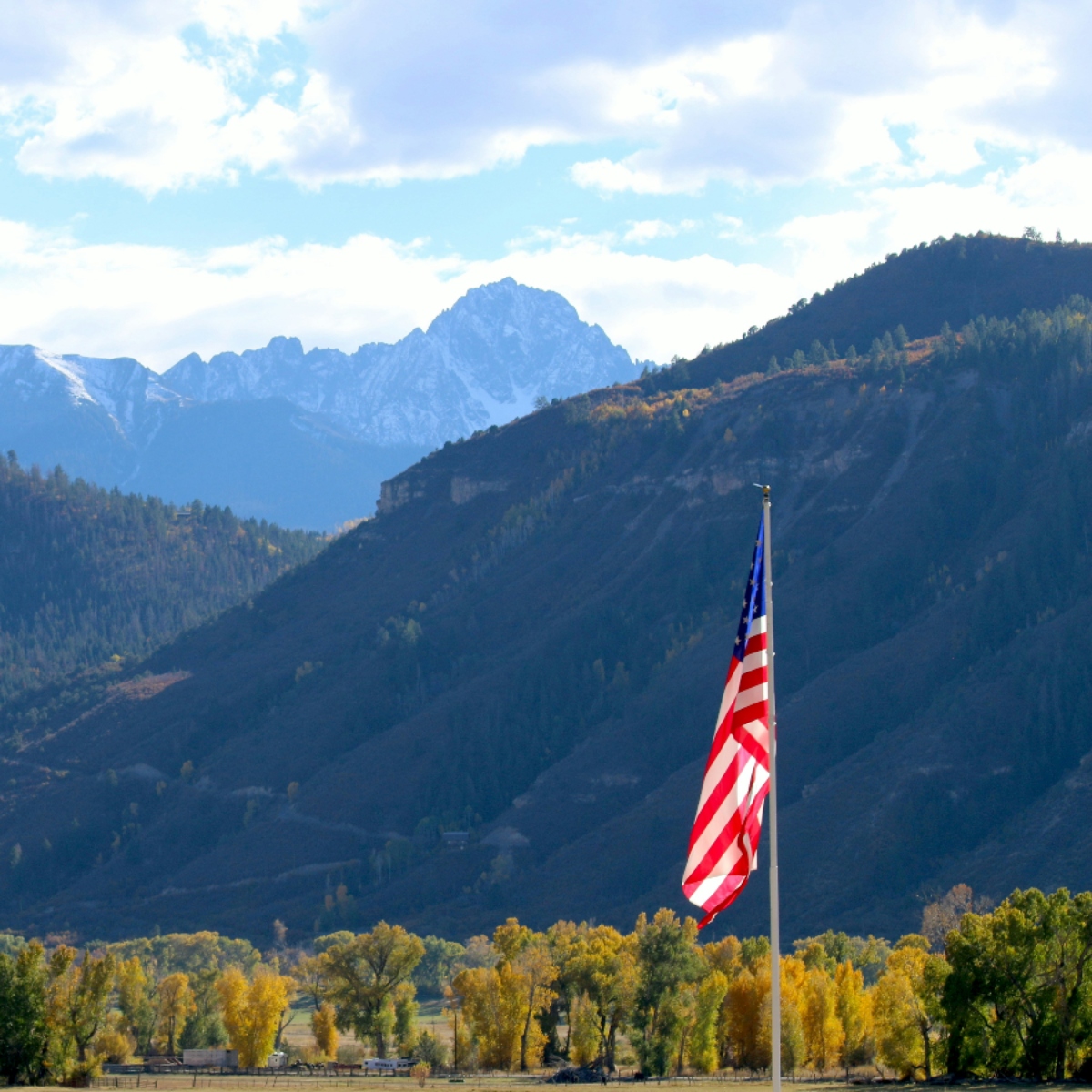 American flag with mountain landscape background.